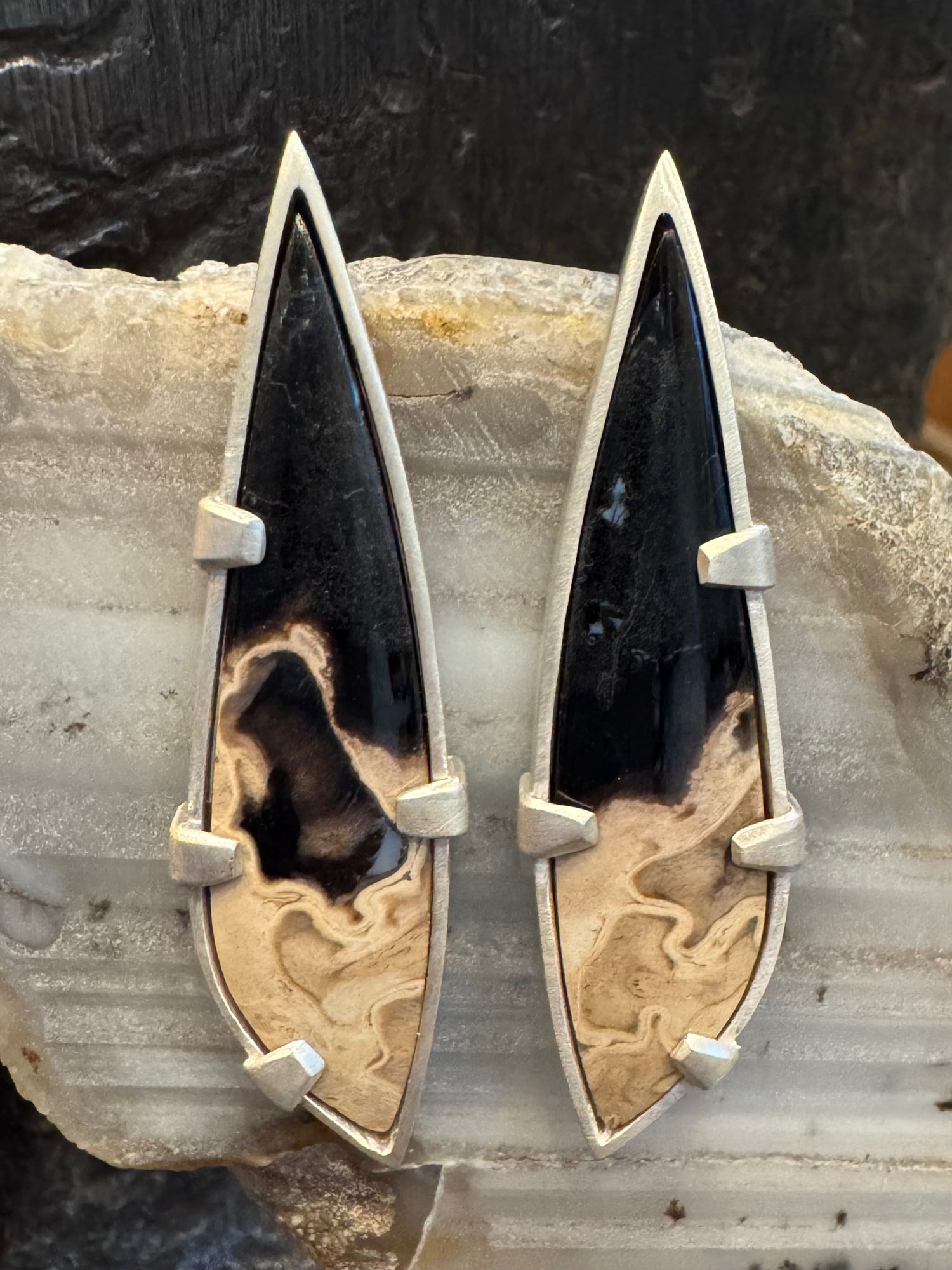 Pair of arrow-shaped sterling silver and stone earrings showing the black and beige natural patterning of the stones and the clean bezel and tab setting of the earrings.
