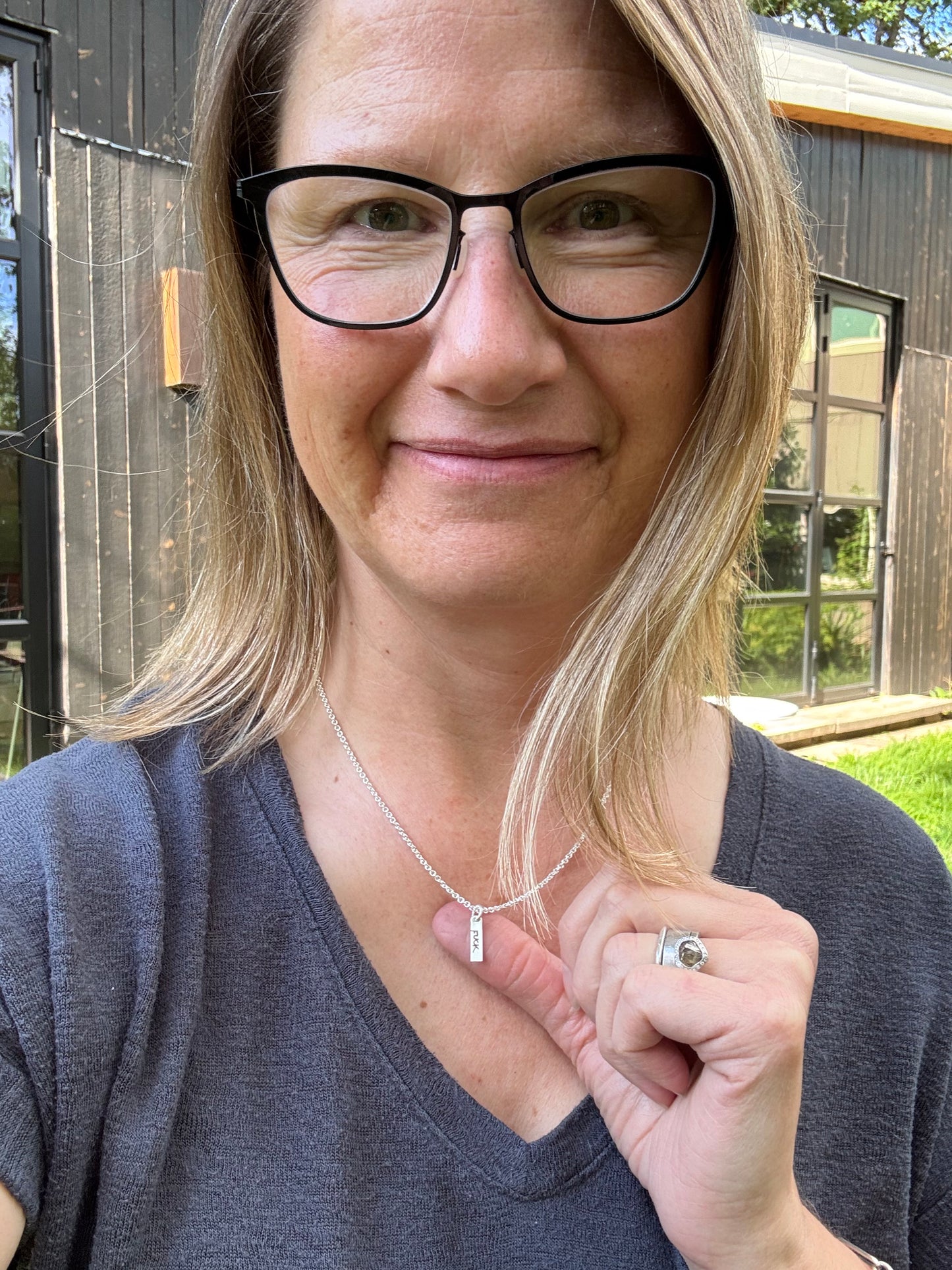 Photo of me wearing a Tiny FUCK necklace, standing in front of my studio.